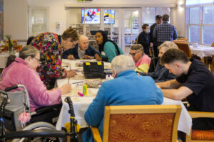 A group of aged care residents in a craft session led by a volunteer